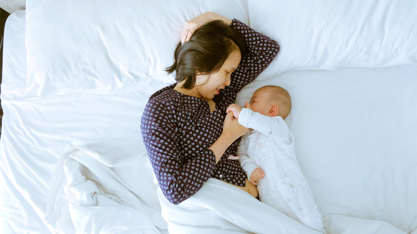 A mom and baby snuggling in bed.